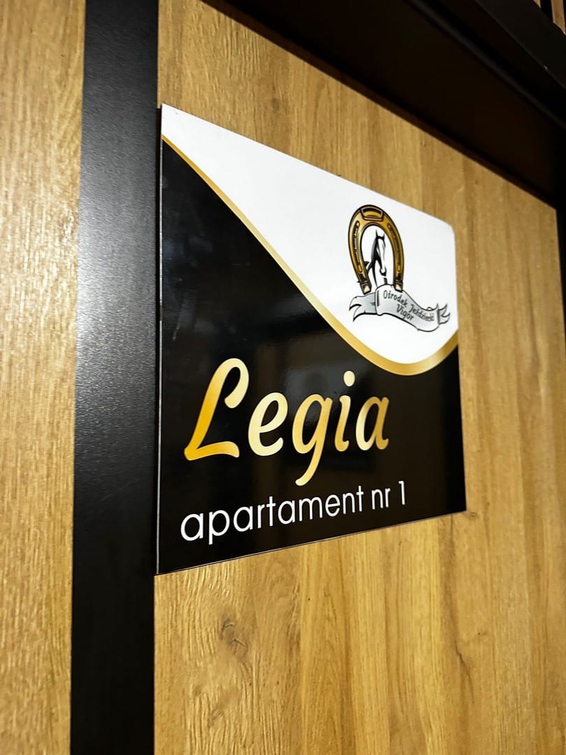 elegancka czarna tabliczka z zlotym napisem legia apartamet legia vigor horses
