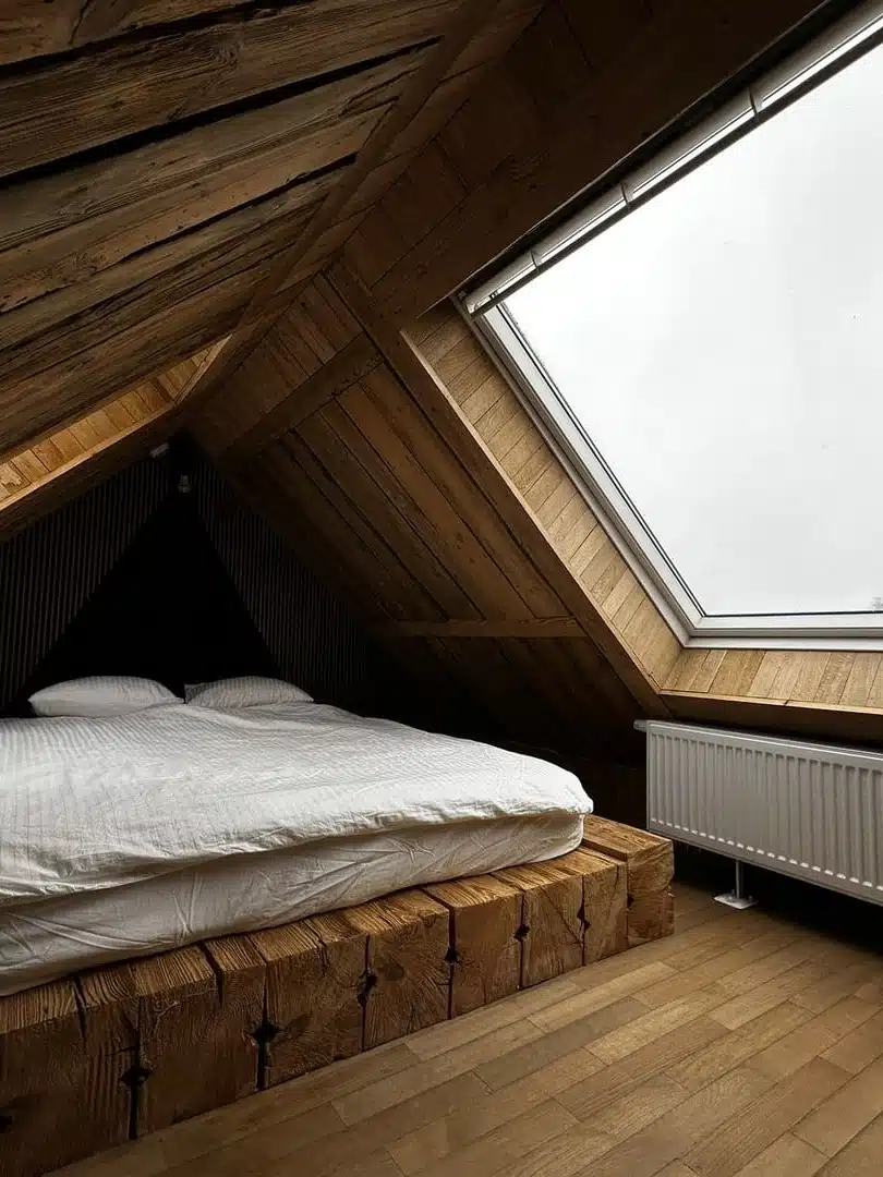 sypialnia na poddaszu z dużym oknem dachowym i ciemnobrązowymi ścianami apartament Karino vigor horses