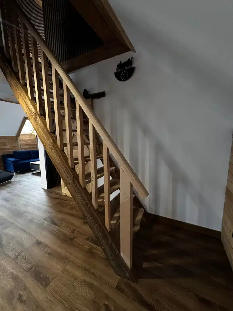 Drewniane schody prowadzące na piętro w apartamencie Karino, Vigor Horses, z detalami wykończenia w ciepłym odcieniu drewna