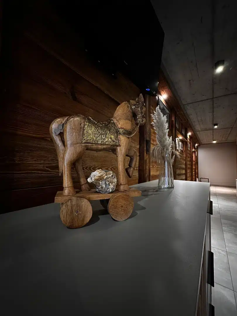 Drewniana rzeźba konia jako element dekoracyjny na szafce w apartamencie Legia, Vigor Horses, dodająca wnętrzu wyjątkowego charakteru końskiego motywu