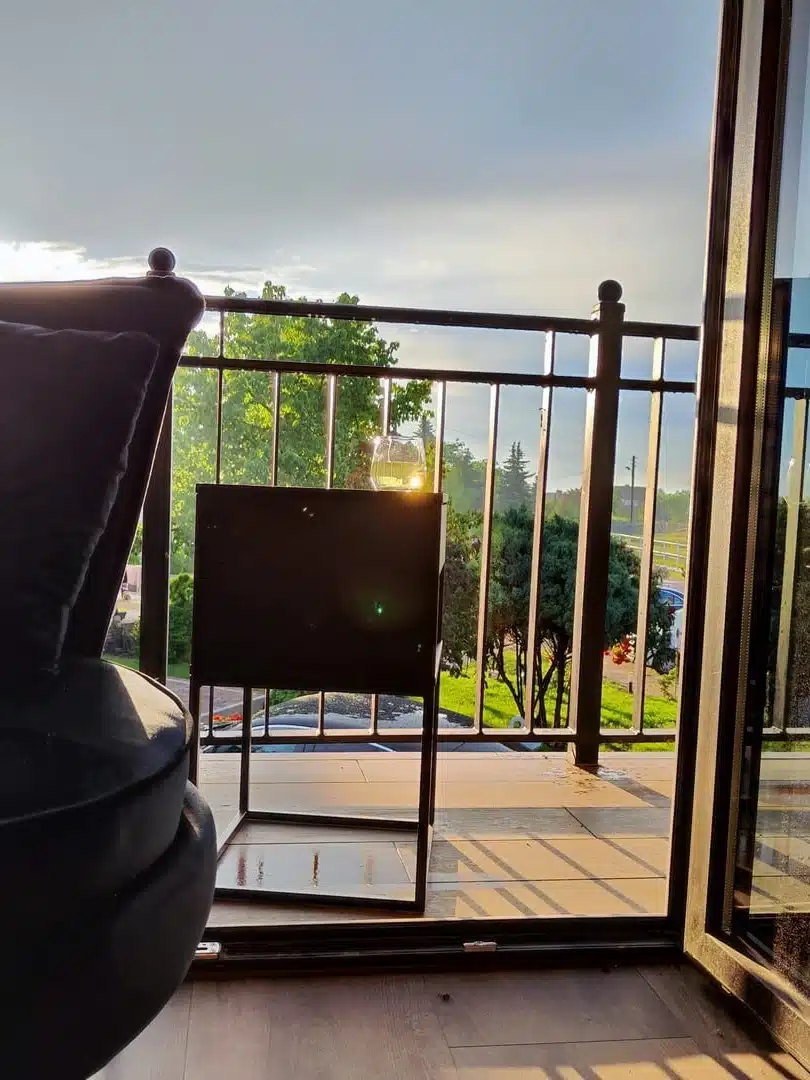 Widok z balkonu apartamentu Merida, Vigor Horses, ukazujący malownicze łąki i kontury koni w oddali, złote promienie słońca dodają magii wieczorowi