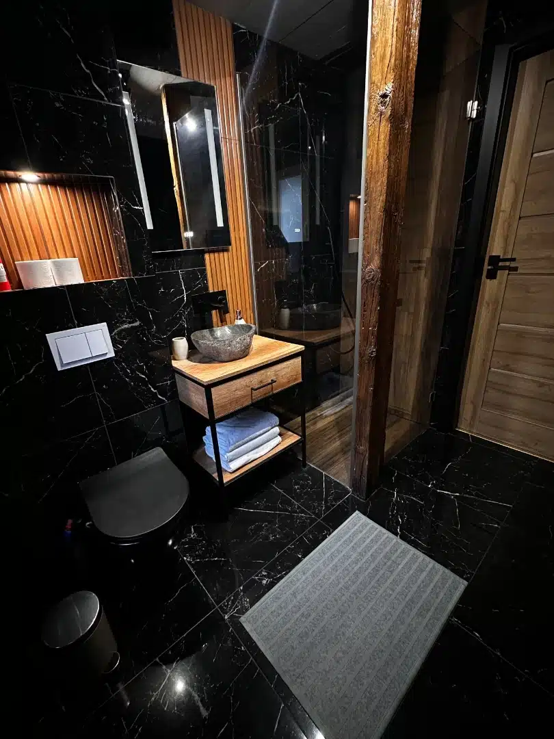Luksusowa łazienka w apartamencie Ursa, Vigor Horses, z marmurowymi płytkami i nowoczesnym wyposażeniem, w tym stylową kamienną umywalką na drewnianej szafce